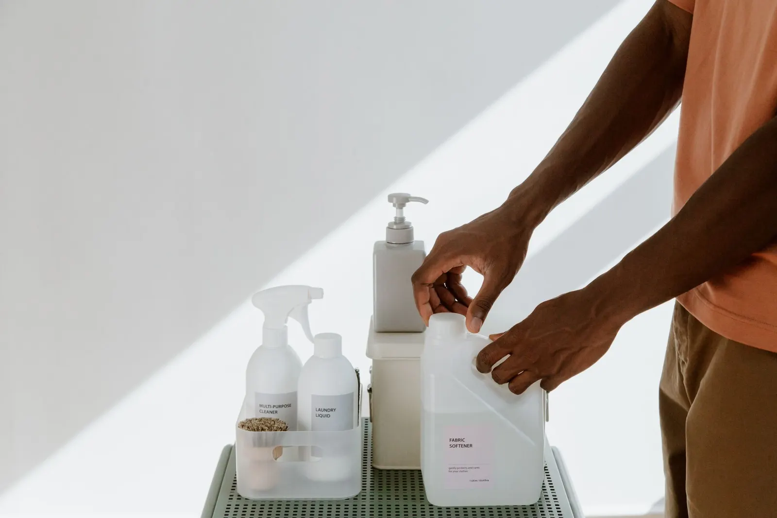 Hands comparing the ingredient labels of two white cleaning product bottles