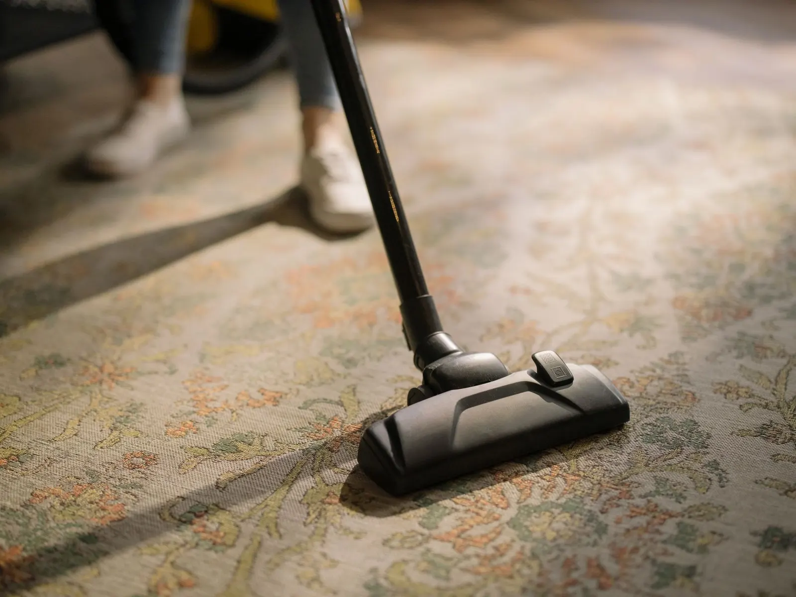 Close-up of a vacuum head passing over a woven area rug